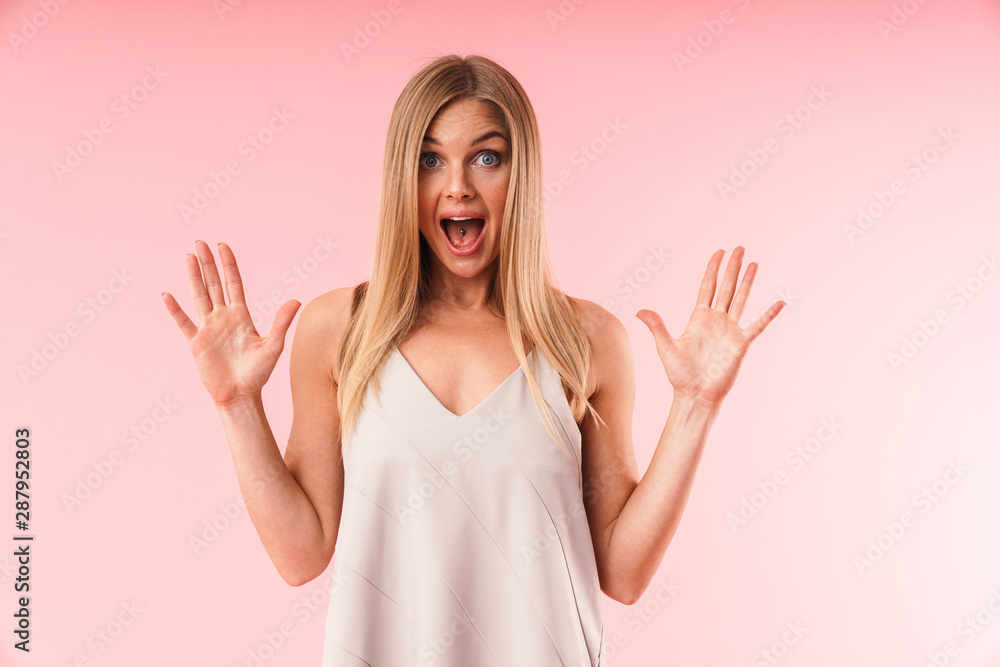 Image of excited blond woman expressing wonder and raising hands while looking at camera