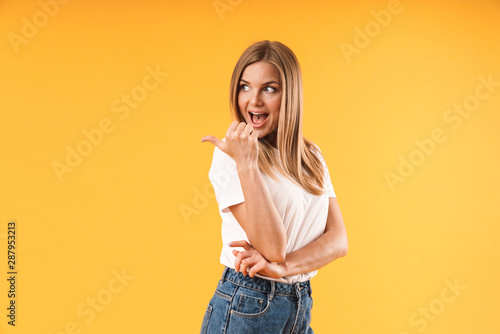 Image of caucasian blond woman wearing casual t-shirt smiling and pointing finger at copyspace