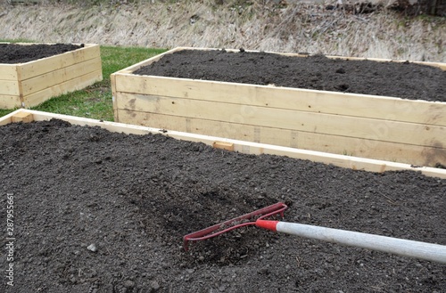 Raking the soil level in newly constructed raised garden boxes.