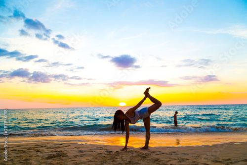 Silhouette yoga sign of healthy women on beach sunset
