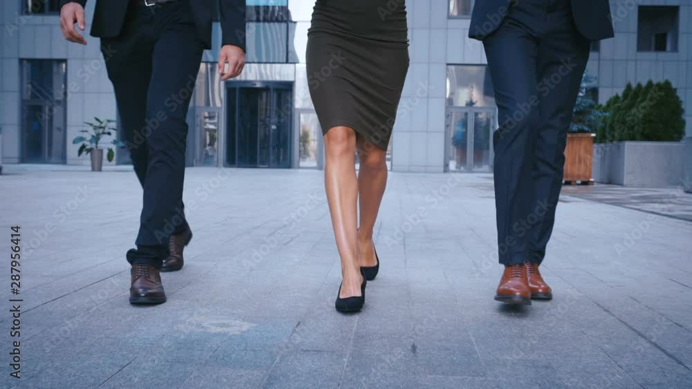 Feet of three business people commuting to work. Businessmen and businesswoman go to office building. Close up legs of Colleagues going in the city outdoor. Feet of three business people commuting to work. Businessmen and businesswoman go to office building. Close up legs of Colleagues going in the city outdoor.