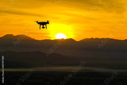 Drone quadcopter flying on mountain sunset silhouette scene