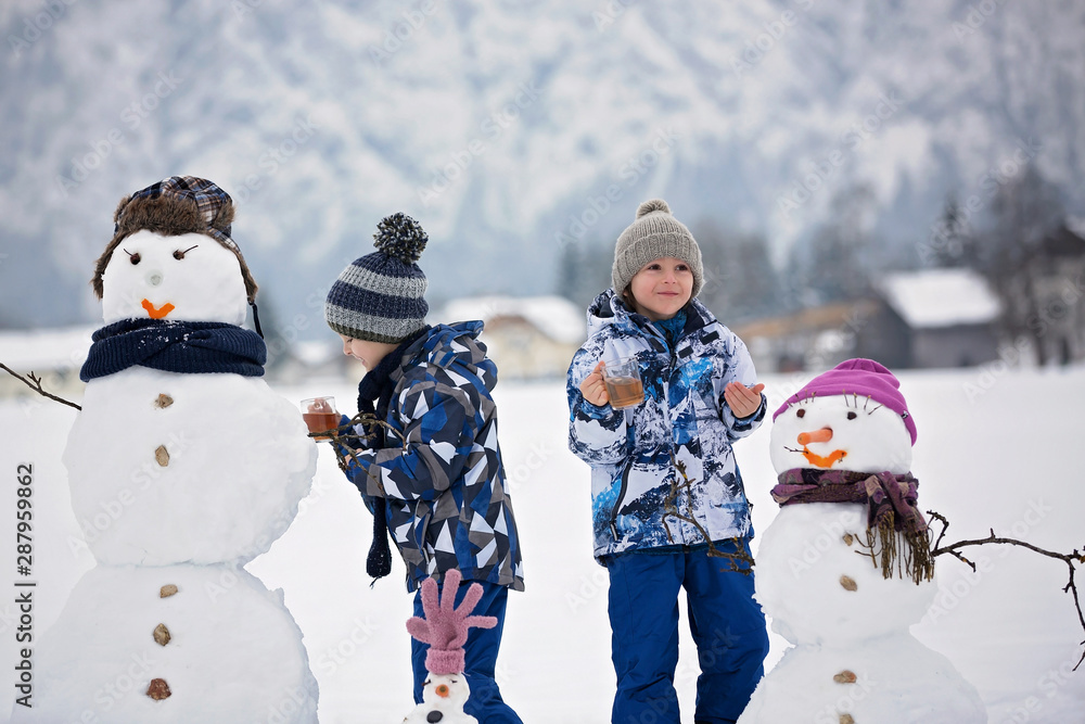 Family with children, building snowman in the park in little village in Austria - obrazy, fototapety, plakaty 
