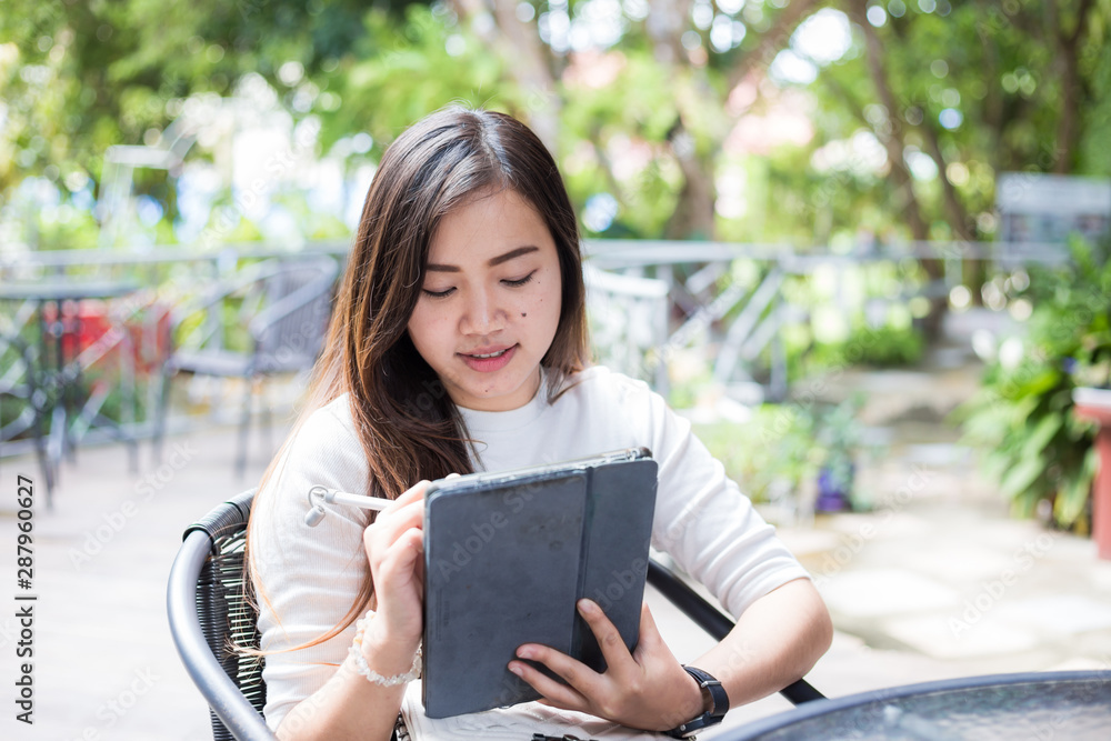 Fototapeta premium Smart asian business women use tablet sitting in coffee shop