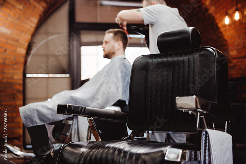 Hipster client in vintage leather chair at barber shop