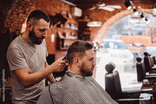 Young modern man getting haircut at luxury salon