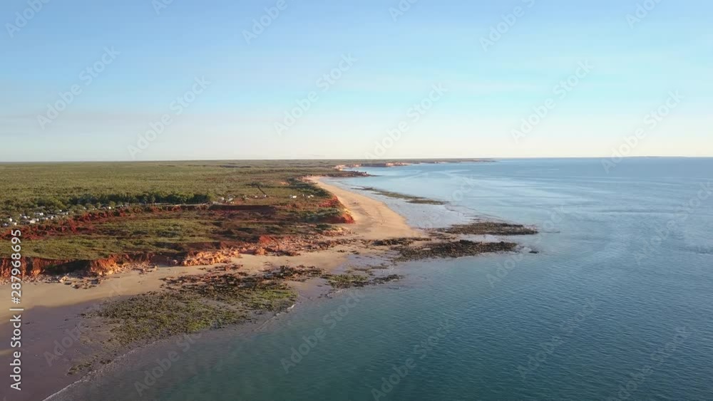 Aerial panoramic view of remote Kimberley coast in Western Australia, with flight along steep rocky cliff, scenic beach and outback landscape as background. Aerial panoramic view of remote Kimberley coast in Western Australia, with flight along steep rocky cliff, scenic beach and outback landscape as background.