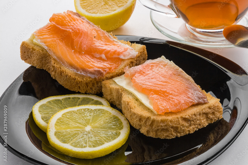 Sandwiches with salted salmon, lemon and a Cup of hot fresh tea Sandwiches with salted salmon, lemon and a Cup of hot fresh tea