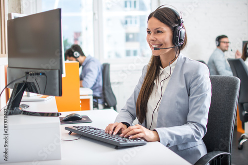Fényképezés Female professional call center telesales agent wear wireless headset using computer in customer care support service office with team