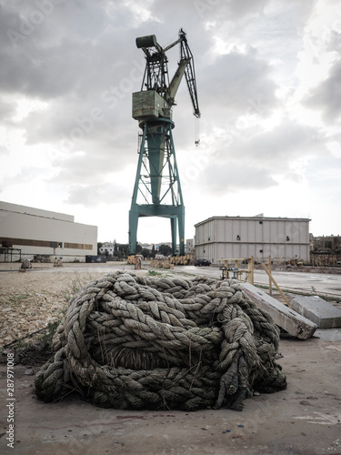 Crane with old rope coiled in front of it.