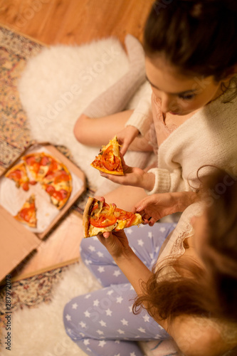fast food  pajama party and people concept - happy female friends eating takeaway pizza at home