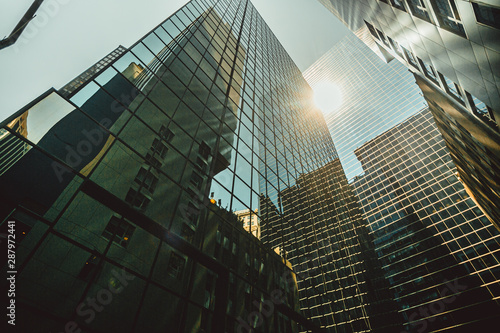 bulding new york - un ensemble de gratte-ciels modernes aux façades en verre réfléchissant la lumière du soleil, créant une vive éclatante.  photo