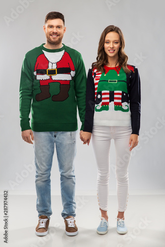 christmas, people and holidays concept - happy couple at ugly sweater party