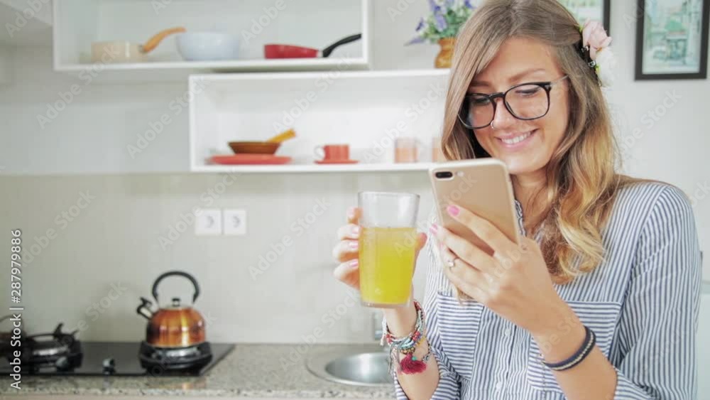Woman using cellphone inside house and drinking juice. Woman using cellphone inside house and drinking juice.