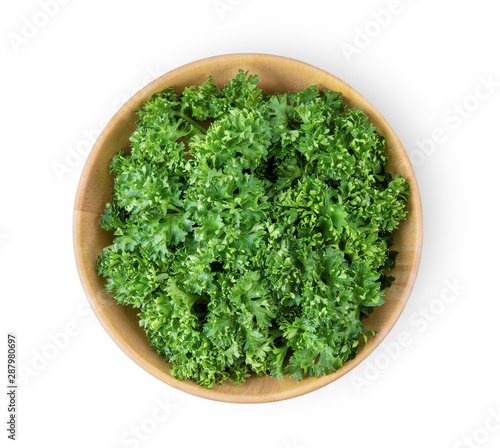 fresh parsley herb in wood bowl isolated on white background. top view