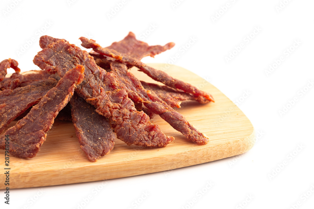 Strips of Beef Jerky on a Wooden Cutting Board Isolated on a White Background Strips of Beef Jerky on a Wooden Cutting Board Isolated on a White Background