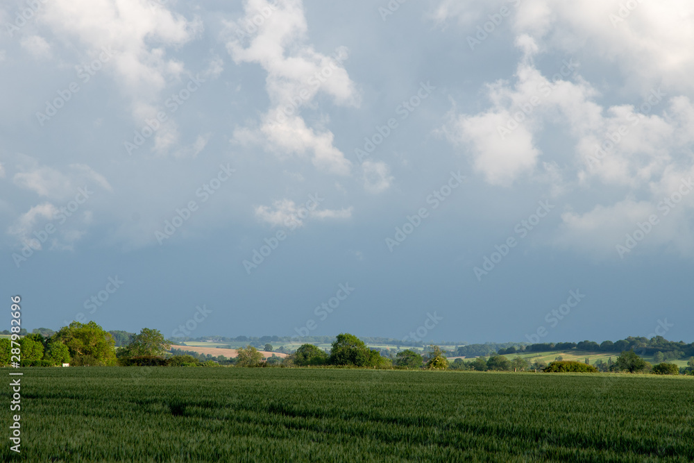 Storm clouds building over green fields and trees on a summer day in the countryside near Shenington, Oxfordshire