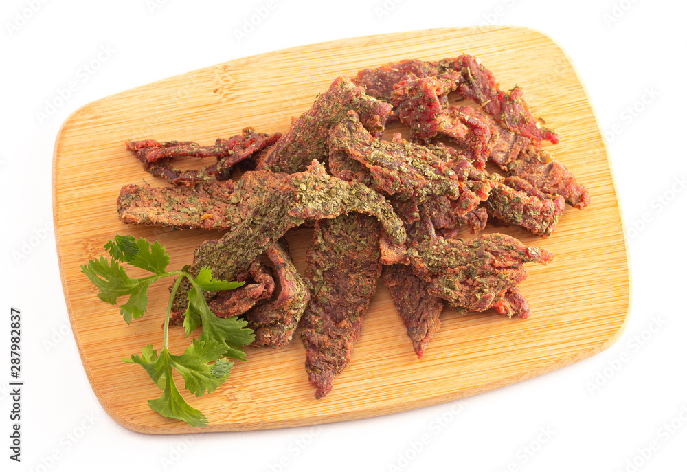 A Pile of Gourmet Cilantro Flavored Beef Jerky on a Wooden Cutting Board A Pile of Gourmet Cilantro Flavored Beef Jerky on a Wooden Cutting Board