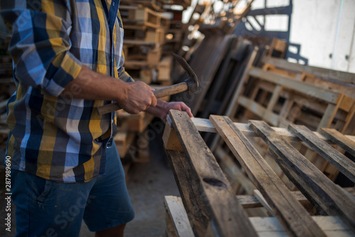 a carpenter repairs wooden pallets