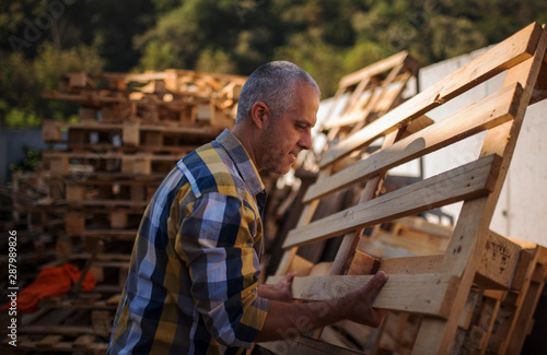a carpenter repairs wooden pallets