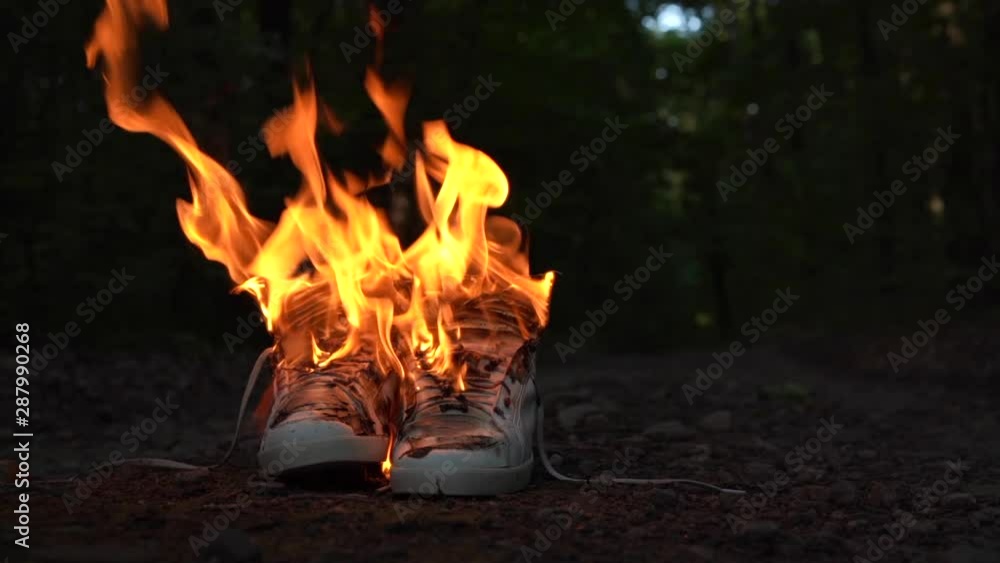 Used white high sneakers burning on a rural road that runs in the forest. Concept. Sport. Nobody comfortable shoes Used white high sneakers burning on a rural road that runs in the forest. Concept. Sport. Nobody comfortable shoes