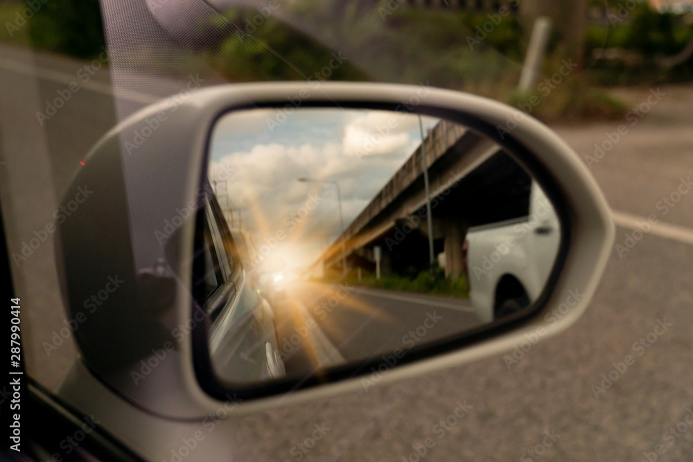 Abstract Blurred image. The view of the side of the mirror white car. with the car from behind with the bright orange light and Bridge.