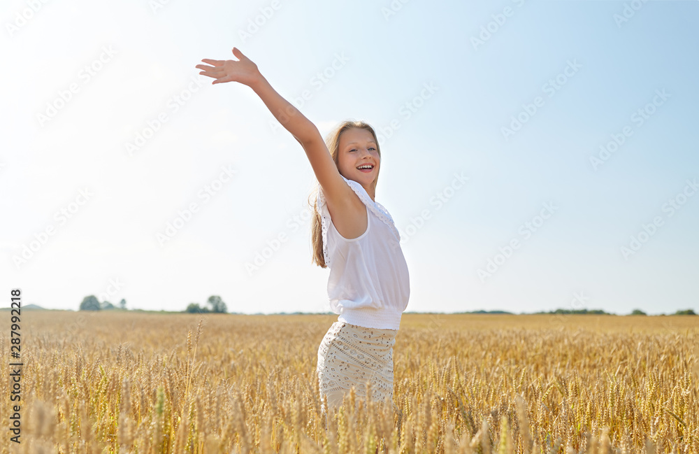 nature, harvest and freedom concept - happy young girl with hands outstretched on cereal field in summer nature, harvest and freedom concept - happy young girl with hands outstretched on cereal field in summer