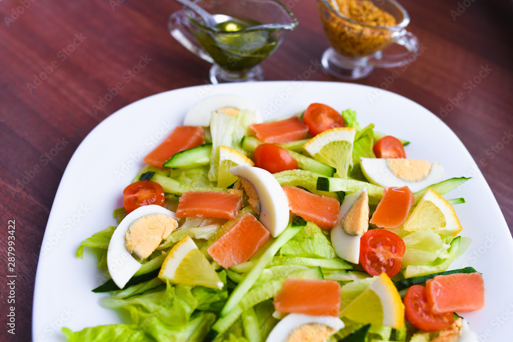 vegetable salad on a white plate. Fresh salad with egg, tomatoes, spinach and avocado on a white wooden background top view. Healthy food.