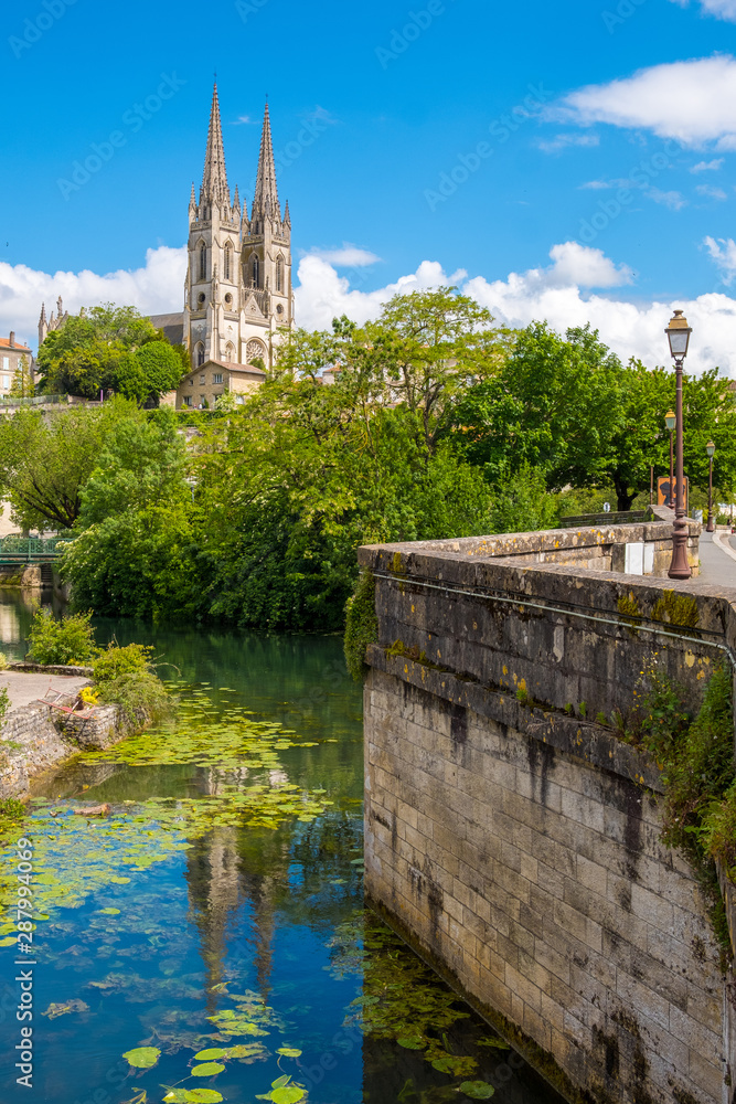 Naklejka premium Steeples of the Saint-Andre church and view of Niort from the quay of Sevre Niortaise river in France