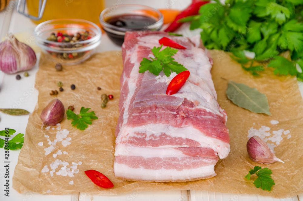 Raw fresh pork belly with salt, pepper, garlic, chili, soy sauce and honey on a white wooden background. Raw fresh pork belly with salt, pepper, garlic, chili, soy sauce and honey on a white wooden background.