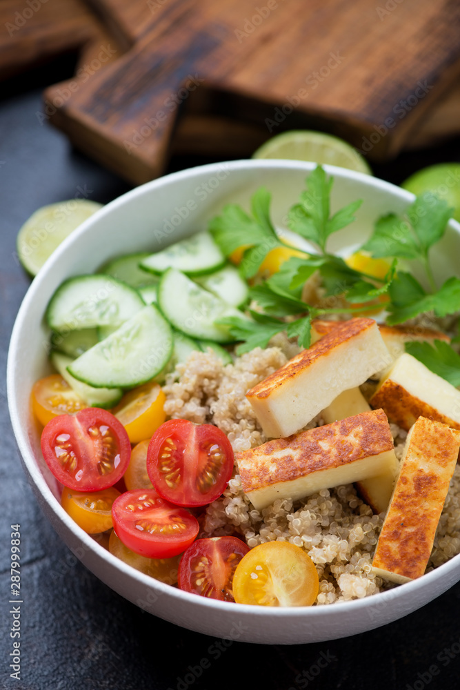 Power bowl with quinoa, roasted cheese, tomatoes, cucumber and parsley, selective focus, closeup