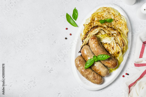 Grilled cabbage steaks with smoked sausages.Top view, copy space.
