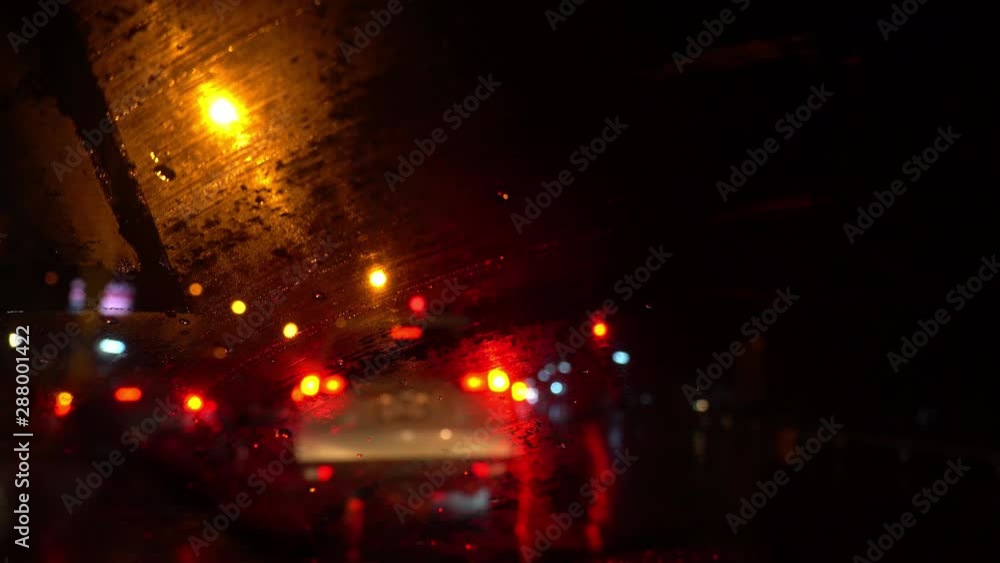 Windscreen wiper the rainy night, With blurred image of traffic congestion on the road. Windscreen wiper the rainy night, With blurred image of traffic congestion on the road.