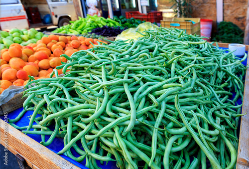 String beans, asparagus, apricots, pears, peppers, plums are sold on the counter.