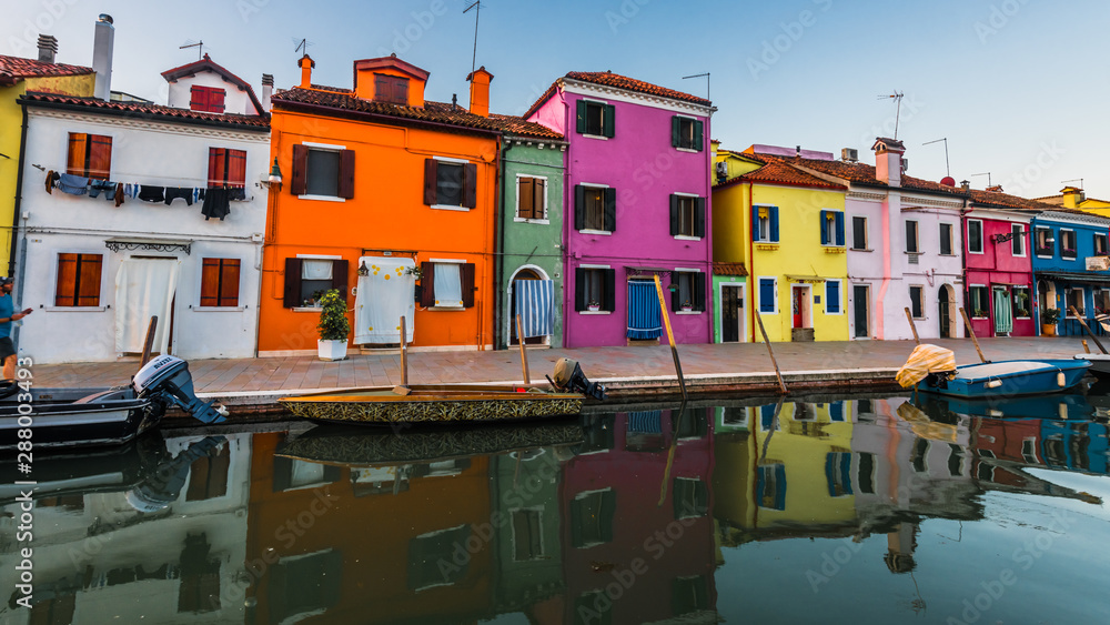 Colorful houses are reflected in the dark waters of the canal
