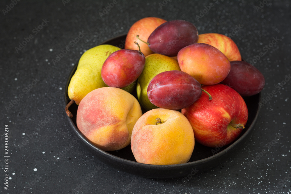 Fruit in a black plate on a black table. Dark background Fruit in a black plate on a black table. Dark background