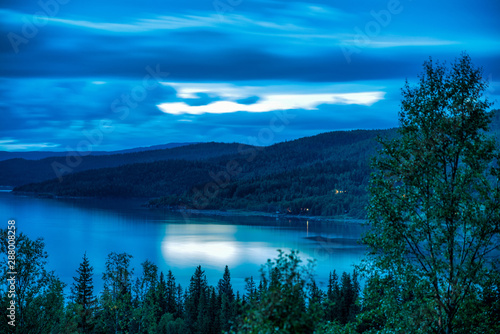 Long exposure photo (30 sec) of heavy clouds over Norwegian mountains around Rossvatnet Lake, Northern Norway. Early summer night.