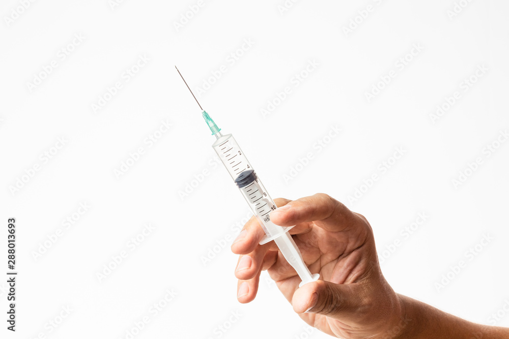 male hand holding a charged syringe and needle for treatment or vaccine campaign male hand holding a charged syringe and needle for treatment or vaccine campaign