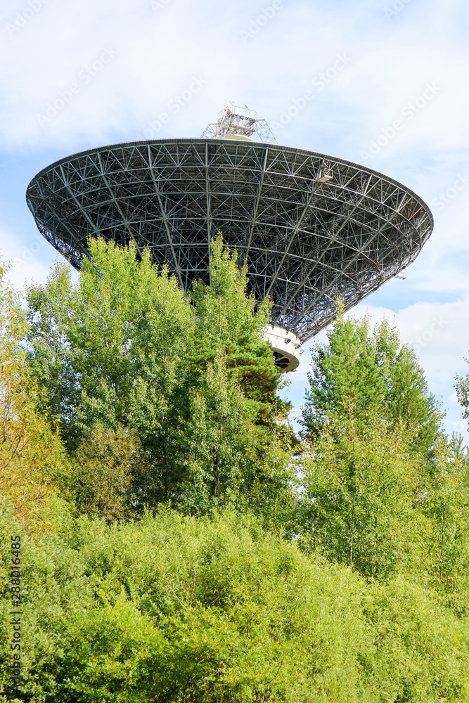 Fototapeta premium Large radio telescope antenna against a blue sky in the forest