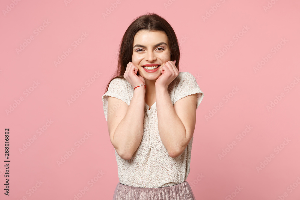 Pretty smiling young woman in casual light clothes posing isolated on pink wall background, studio portrait. People sincere emotions lifestyle concept. Mock up copy space. Clenching fists near cheeks. Pretty smiling young woman in casual light clothes posing isolated on pink wall background, studio portrait. People sincere emotions lifestyle concept. Mock up copy space. Clenching fists near cheeks.