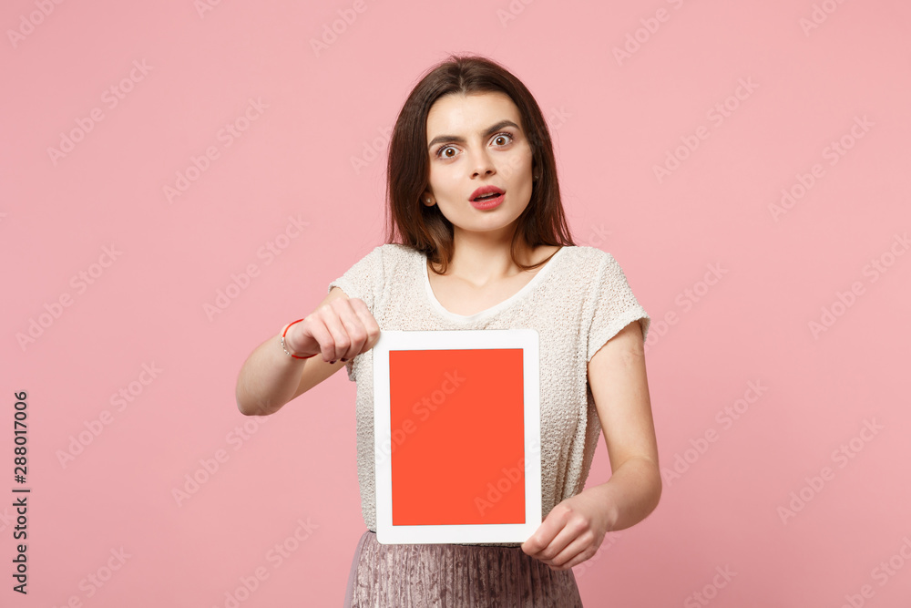 Shocked young woman in casual light clothes posing isolated on pastel pink background studio portrait. People lifestyle concept. Mock up copy space. Holding tablet pc computer with blank empty screen. Shocked young woman in casual light clothes posing isolated on pastel pink background studio portrait. People lifestyle concept. Mock up copy space. Holding tablet pc computer with blank empty screen.