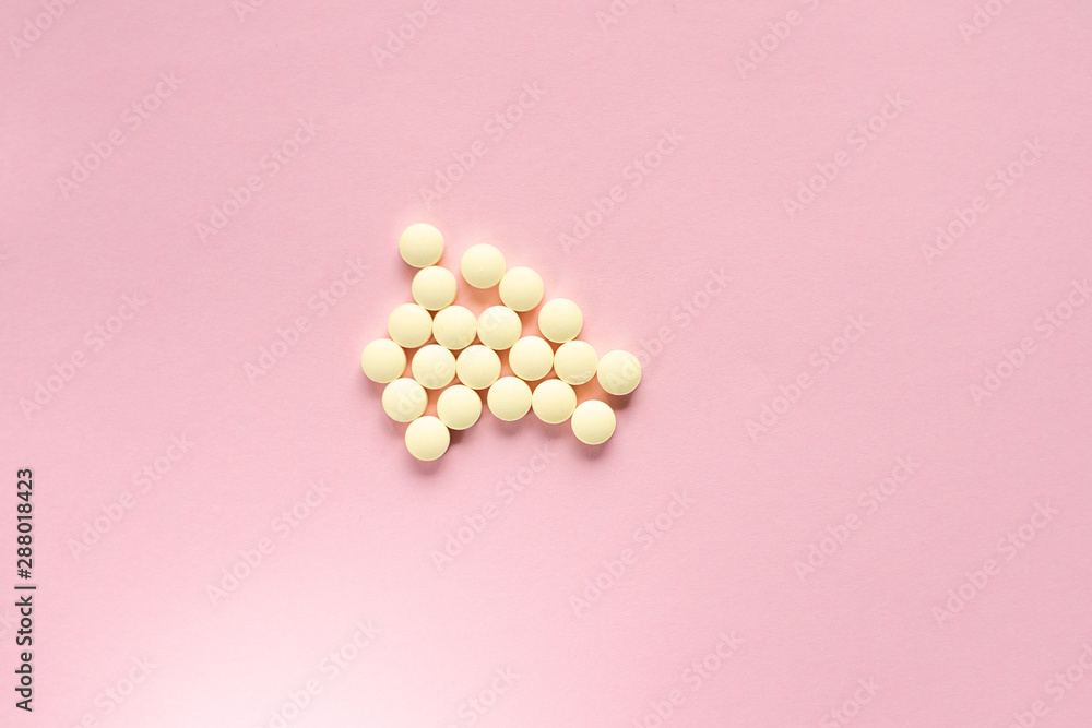 Yellow pills on a pale pink background Yellow pills on a pale pink background
