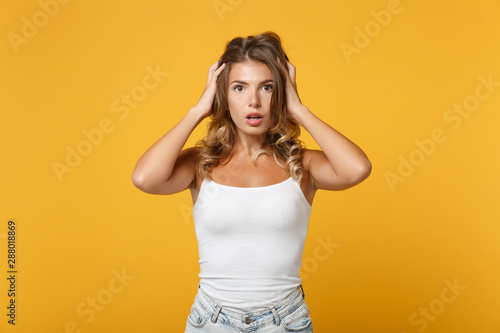 Shocked young woman girl in light casual clothes posing isolated on yellow orange wall background studio portrait. People sincere emotions lifestyle concept. Mock up copy space. Putting hands on head.