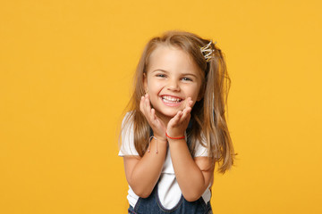 Little cute child kid baby girl 4-5 years old wearing light denim clothes isolated on pastel yellow wall background, children studio portrait. Mother's Day, love family, parenthood childhood concept.