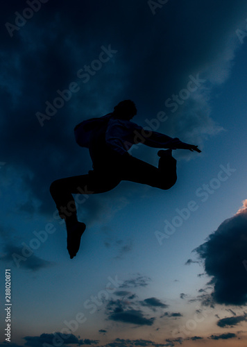 A jumping silhouette man on the sunset background