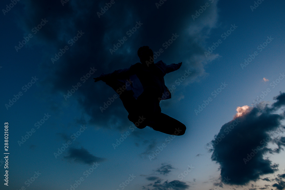 Silhouette of excited male dancer leaping at the sky