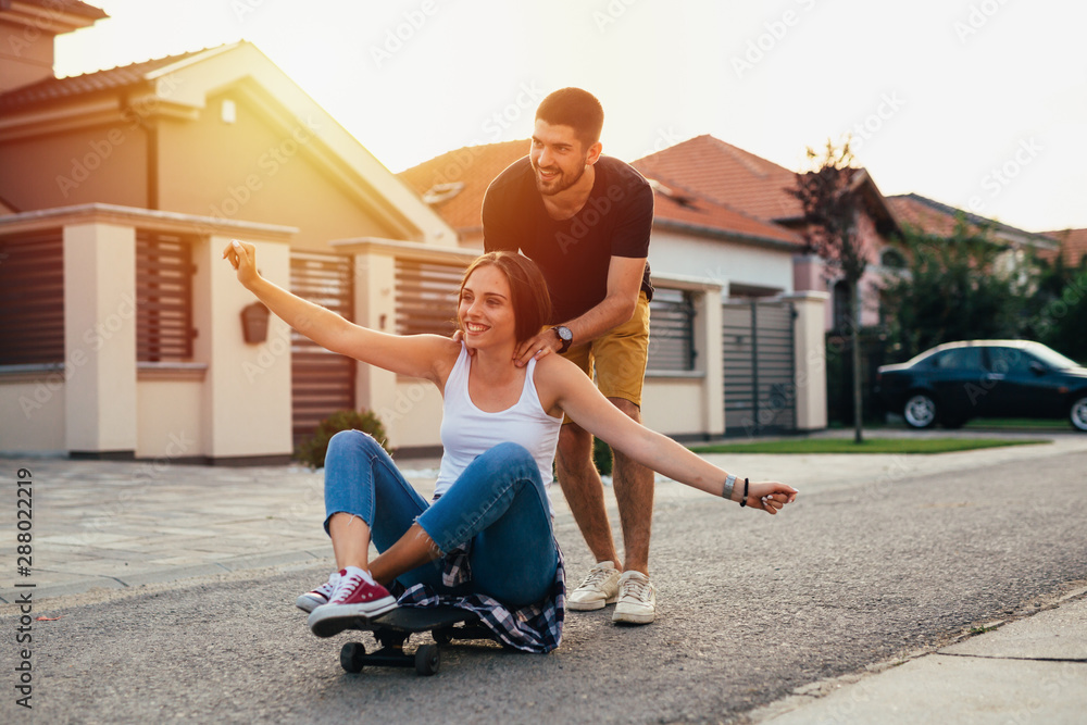 young couple having fun while driving skateboard outdoor