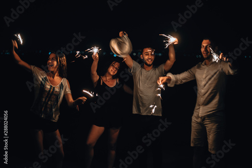 Picture showing young silhouette couple having fun with sparklers, low key, dark image