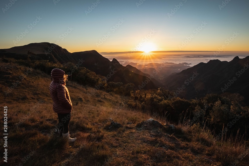 pessoa observando o nascer do sol no alto da montanha 