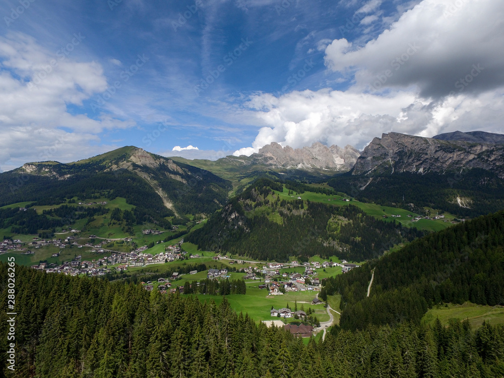 Aerial of Val Gardena from Ciampinoi in Gröden. Stevia and Seceda in the Background and Forest and Trees in the foreground. Drone Image of the Dolomites
